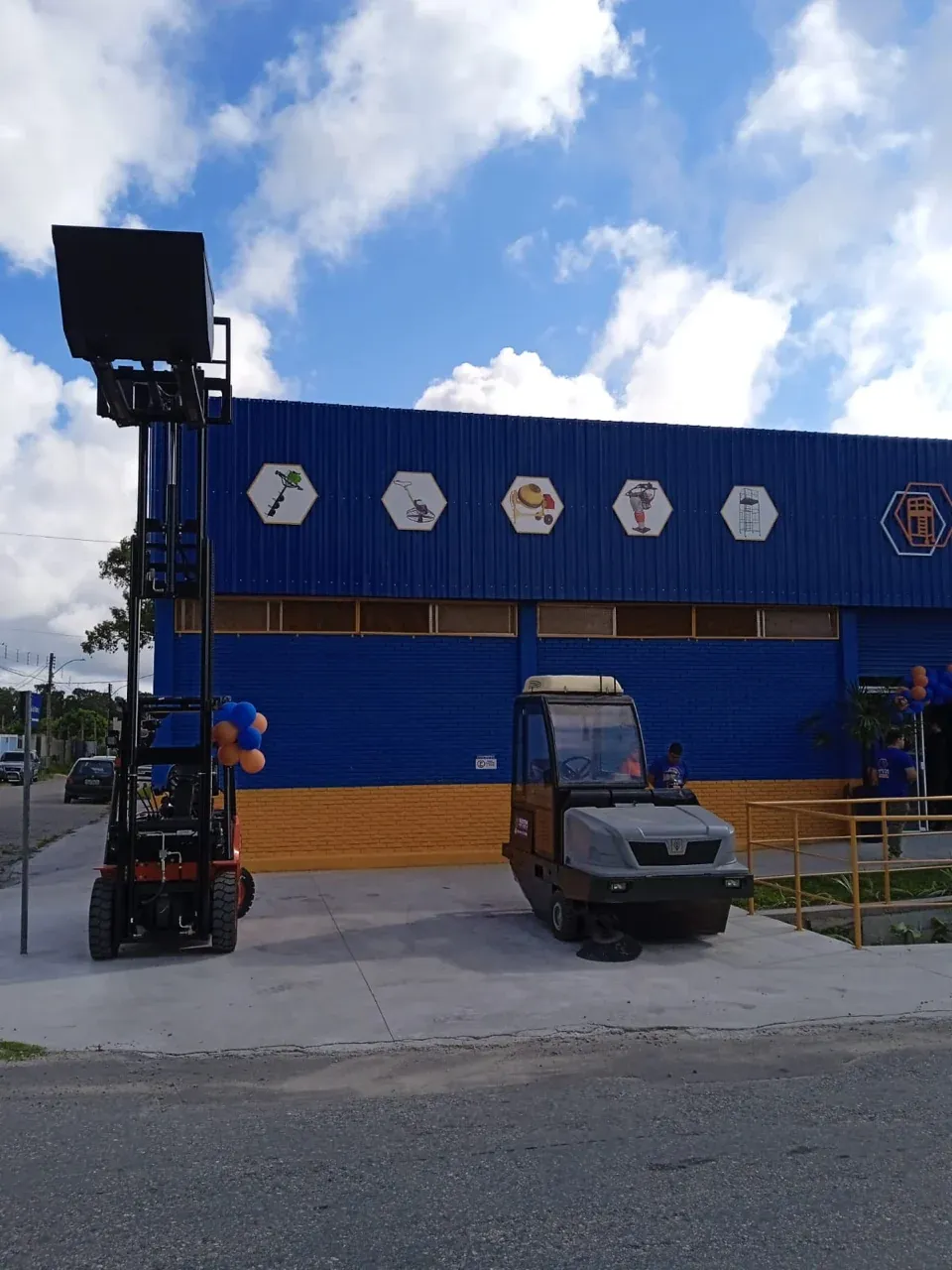 Fachada da loja Mestre da Obra em Rio Grande: prédio azul com base laranja e hexágonos com pictogramas de equipamentos